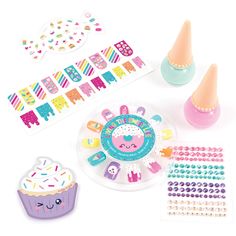 an assortment of stickers, cupcakes and decorations on a white table top