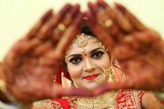 a woman in red and gold is holding her hands up to show off her face