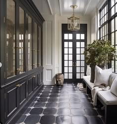 a hallway with black and white tile flooring next to a large glass front door