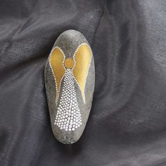 a pair of painted rocks sitting on top of a black cloth with gold and white designs