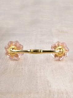 a pair of pink glass knobs on a wooden surface with a gold colored handle