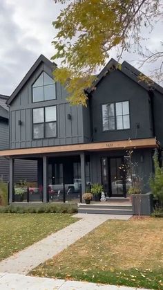 a large gray house sitting on top of a lush green field