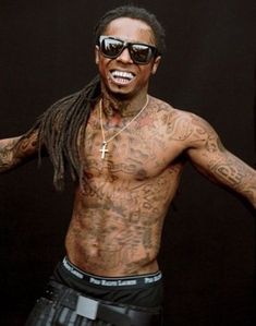 a man with dreadlocks and tattoos on his chest is dancing in front of a black background