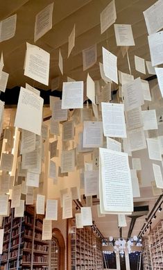 many books are hanging from the ceiling in a room with lots of paper on it