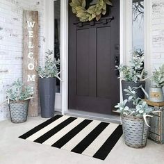 the front door is decorated with potted succulents and a welcome mat