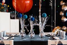 the table is set with silver and blue decorations, balloons, and confetti