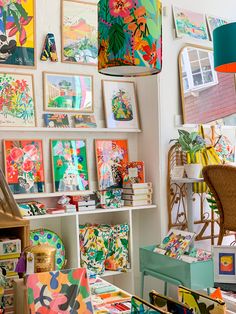 a room filled with lots of colorful pictures and paintings on the wall next to a chair