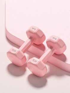 two pink dumbbells sitting next to each other on top of a white surface