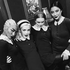 four women dressed in black and white posing for the camera