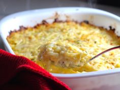 a spoon full of macaroni and cheese in a white casserole dish