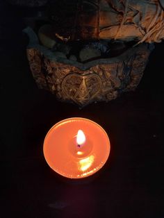 a lit candle sitting on top of a table next to a bowl filled with rocks