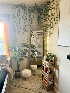 a living room filled with lots of plants next to a mirror and bookshelf