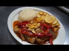 a white plate topped with meat and veggies covered in sauce next to rice