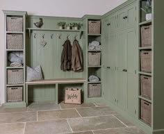 a mud room with green cabinets and wicker baskets