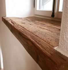 a wooden shelf sitting in front of a window next to a white wall and door