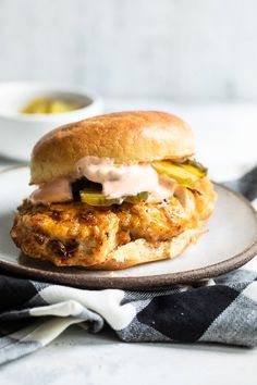 a chicken sandwich with pickles and mayonnaise on a plate