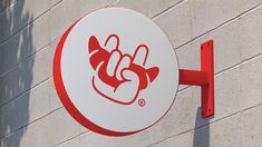 a red and white sign hanging from the side of a building next to a brick wall