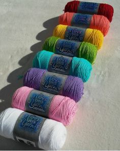 several skeins of yarn are lined up on the floor with each one in different colors