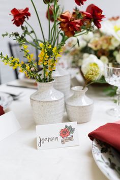 the table is set with vases and place cards for guests to write their names