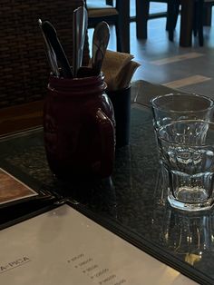 there are two glasses on the table with utensils in each glass and an empty cup next to it