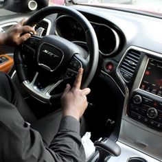 a man driving a car while holding the steering wheel with both hands and pressing buttons