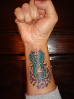 a woman's wrist tattoo with an aqua ribbon and the word hope on it