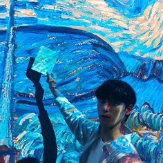 a young man is painting an image with blue and yellow colors on the wall in front of him