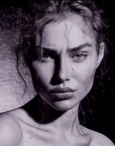 a black and white photo of a woman's face with water on her body