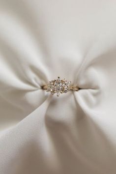 an engagement ring on top of a white satin fabric with diamond stones in the center