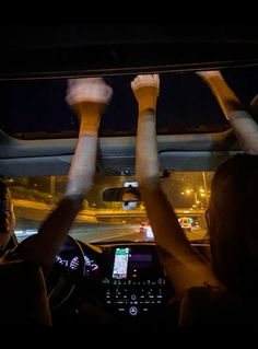 two people driving in the dark with their hands up