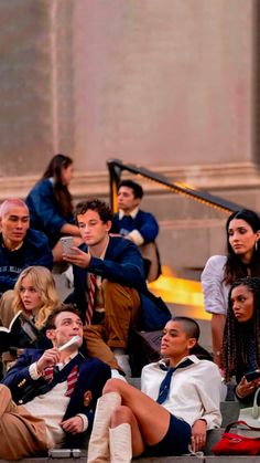 a group of people sitting next to each other in front of a building and one person taking a selfie