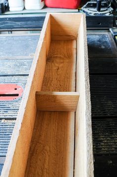 an empty wooden box sitting on top of a table next to a red toolbox