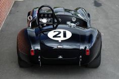 an old fashioned race car with the number twenty on it's front wheel drive down a street