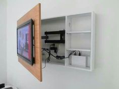 a tv mounted to the side of a white wall next to a wooden framed object