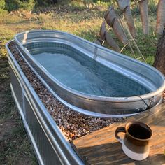 a hot tub sitting on top of a wooden table next to a cup of coffee