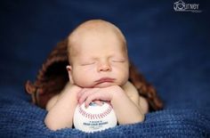 a baby is sleeping with her head on a baseball