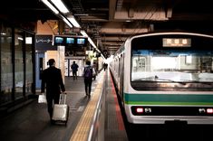 a subway train pulling into the station with people walking on the platform next to it