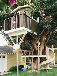 a tree house with a slide in the yard