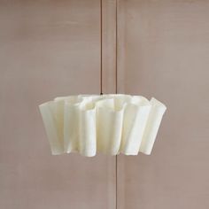 a light fixture hanging from the ceiling in front of a beige wall with white curtains