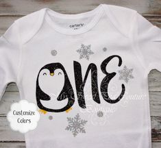 a white onesie with a penguin and snowflakes on it's chest