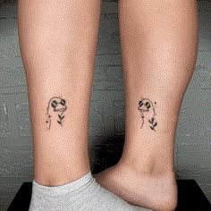 two people with matching tattoos on their legs, one has a flower and the other has a bird