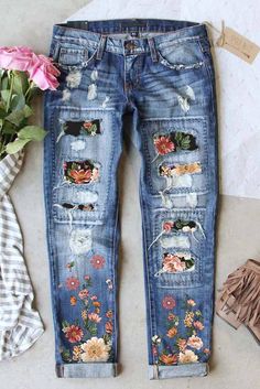 a pair of ripped jeans with flowers on them