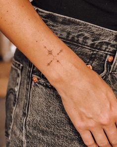 a woman's arm with a small cross tattoo on the left side of her wrist