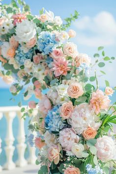 an arrangement of flowers and greenery on the beach