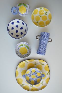 a table topped with bowls and plates covered in yellow and blue designs on white counter top