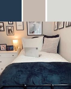 a bed with white pillows and blue sheets in a room that has pictures on the wall