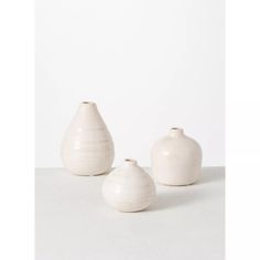 three white vases sitting next to each other on a table