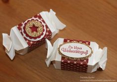 two red and white boxes with gold designs on them sitting on a wooden table next to each other