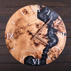 a wooden clock with black and white paint on it's face, showing the time in roman numerals