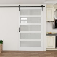 an open sliding door in a kitchen with wood floors and white walls, along with a potted plant